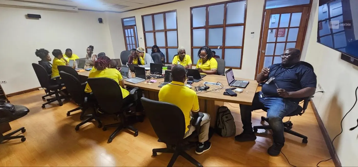 Willard Wells facilitating a hands-on AI workshop for Jamaica Public Service staff, August 2026 — participants working on laptops in a boardroom